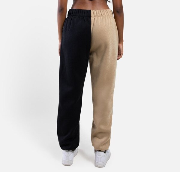 The back of two toned color blocked sweatpants, where the right leg is gold and the left leg is black.
